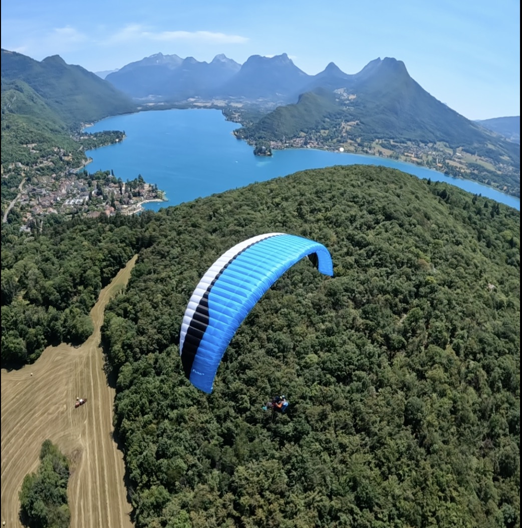 Parapente biplace en vol au-dessus du lac d’Annecy et des montagnes environnantes