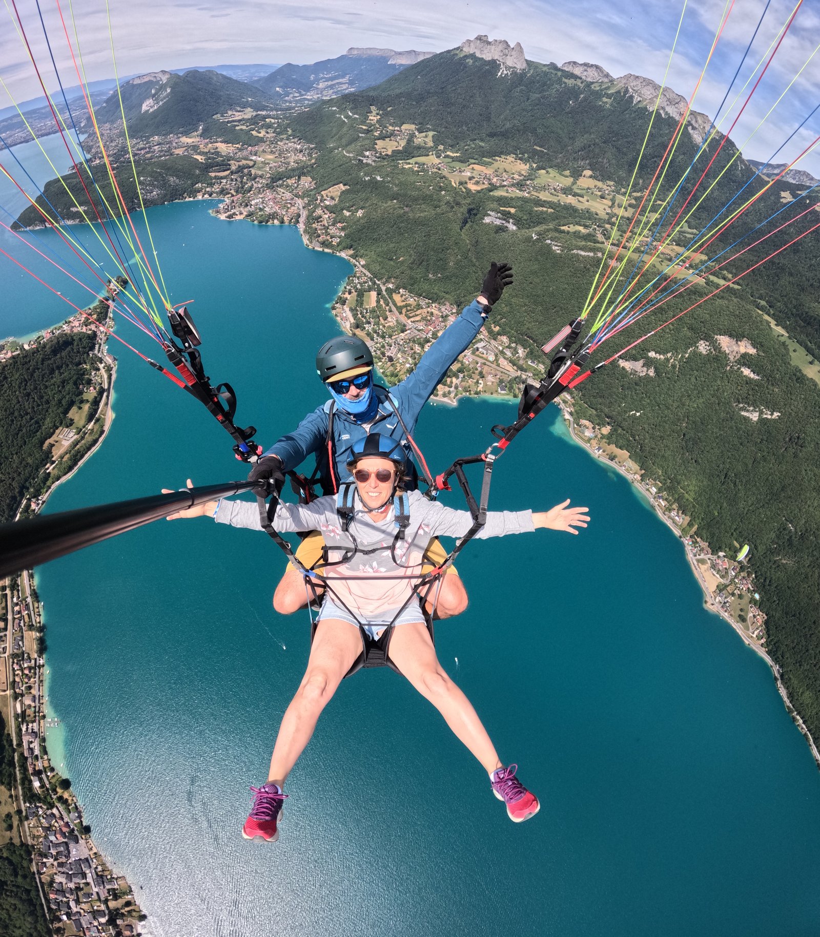 Passagère souriante pendant un vol en parapente biplace au-dessus du lac d’Annecy