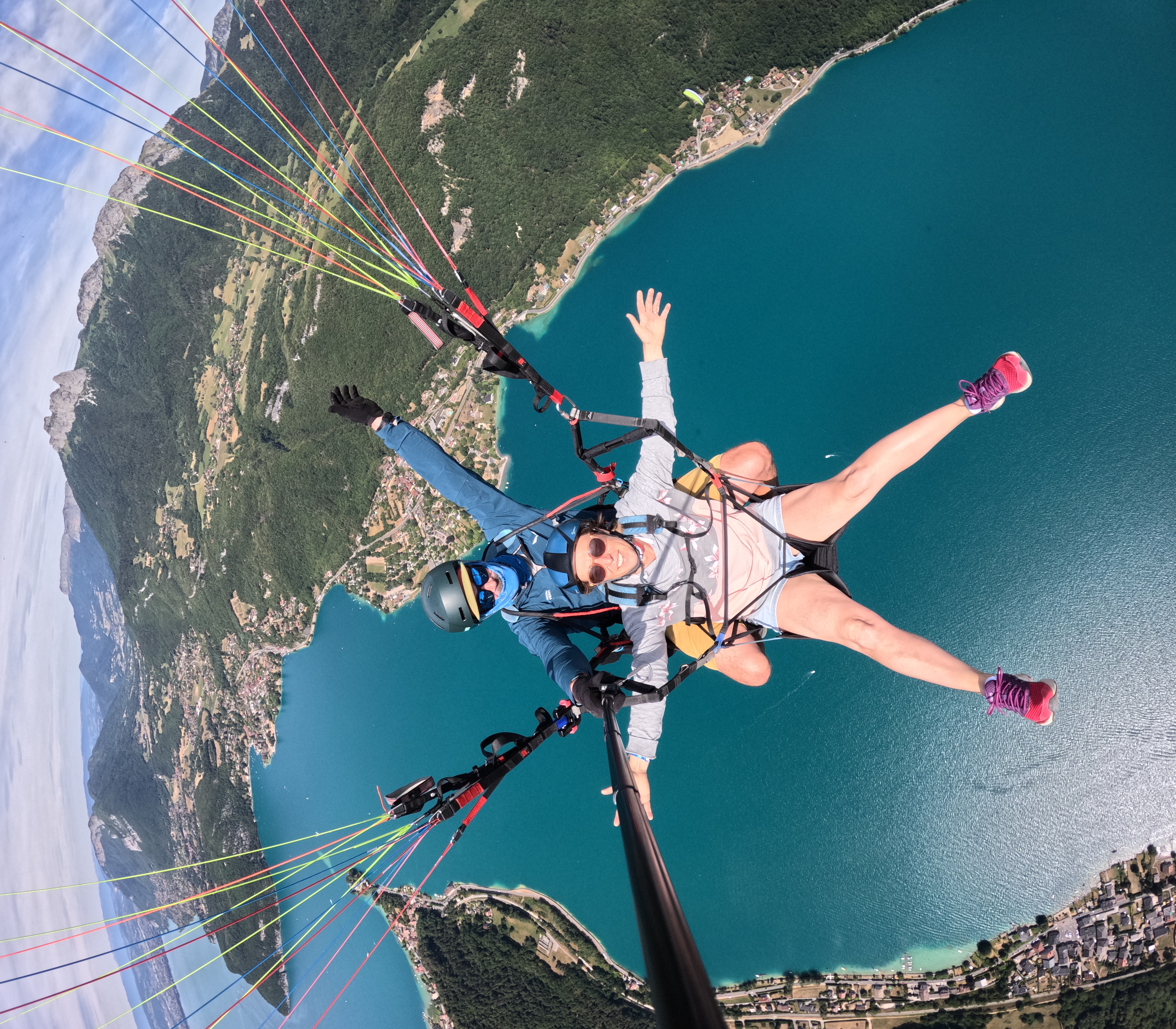 Passagère souriante pendant un vol en parapente biplace au-dessus du lac d’Annecy