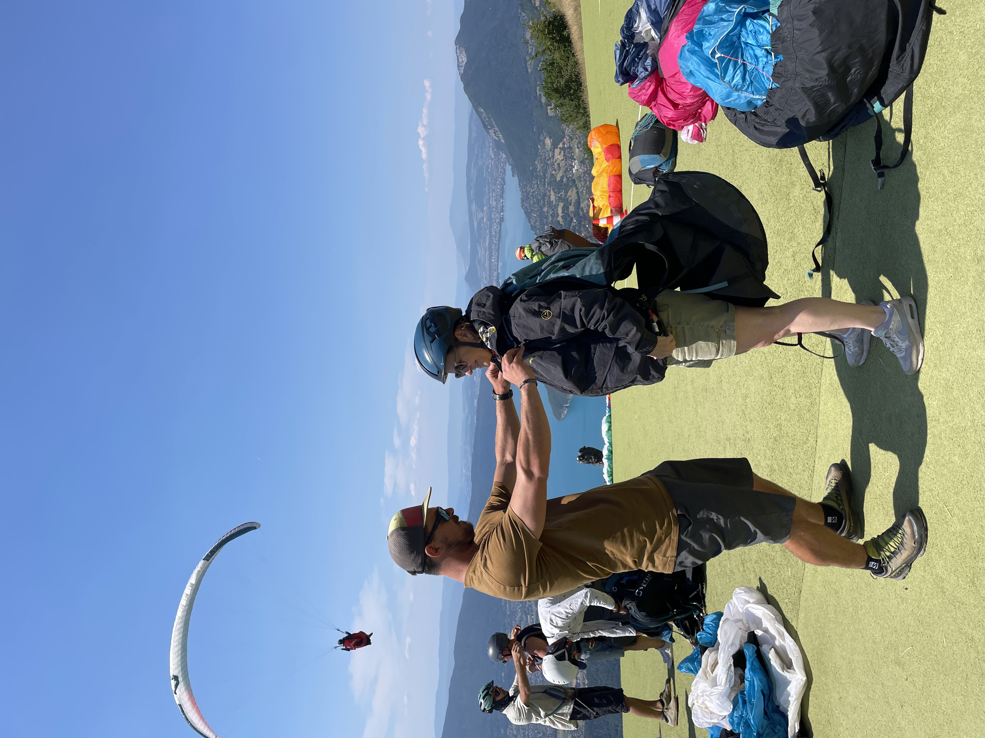 Moniteur ajustant l’équipement d’un passager avant un décollage en parapente