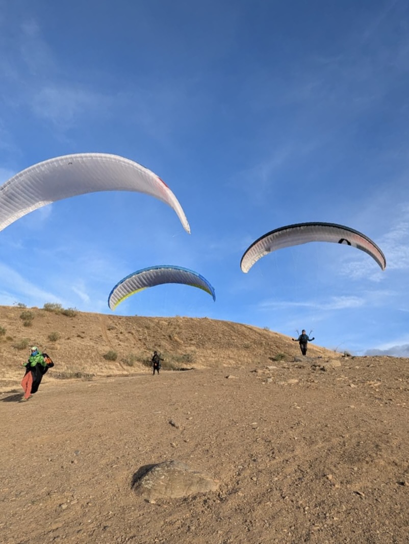 Trois pilotes au décollage en parapente sur un site poussiéreux d’Andalousie