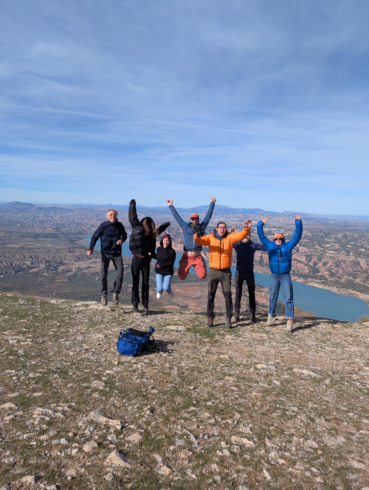 Groupe de pilotes fêtant l’arrivée au sommet, avec la retenue d’eau de la Sierra Nevada en contrebas