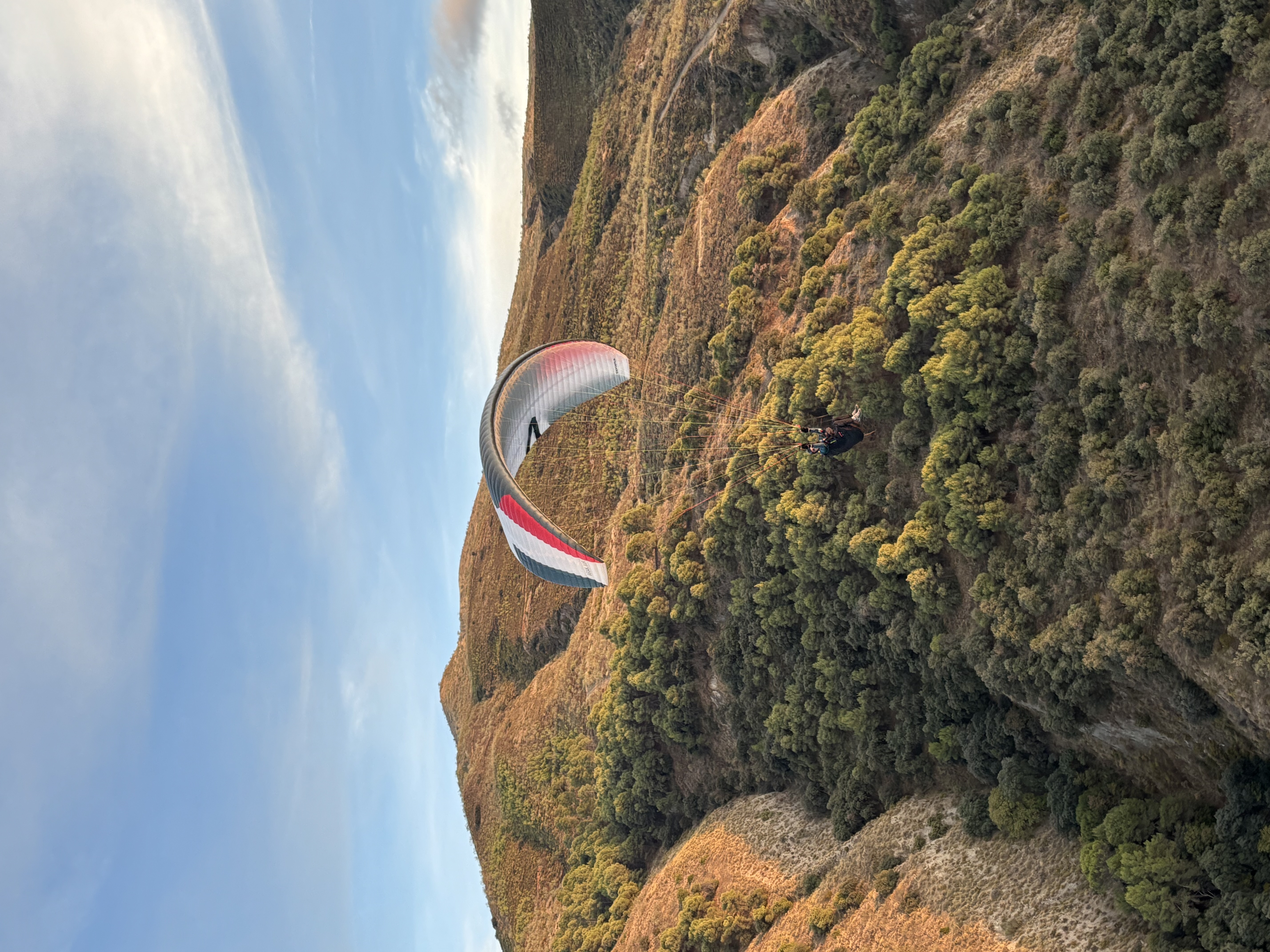 Pilote en vol thermique en parapente au-dessus des reliefs andalous