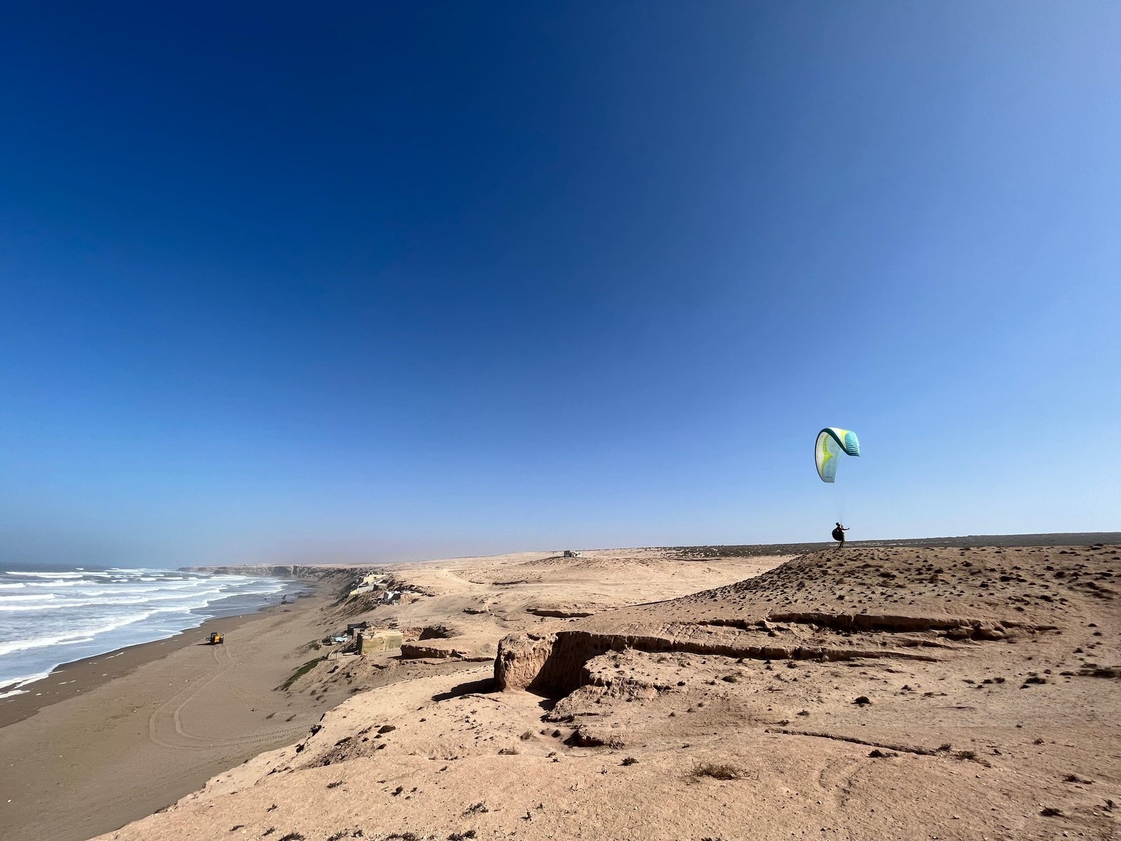 Pilote au décollage en parapente sur les falaises côtières face à l’océan Atlantique, au Maroc