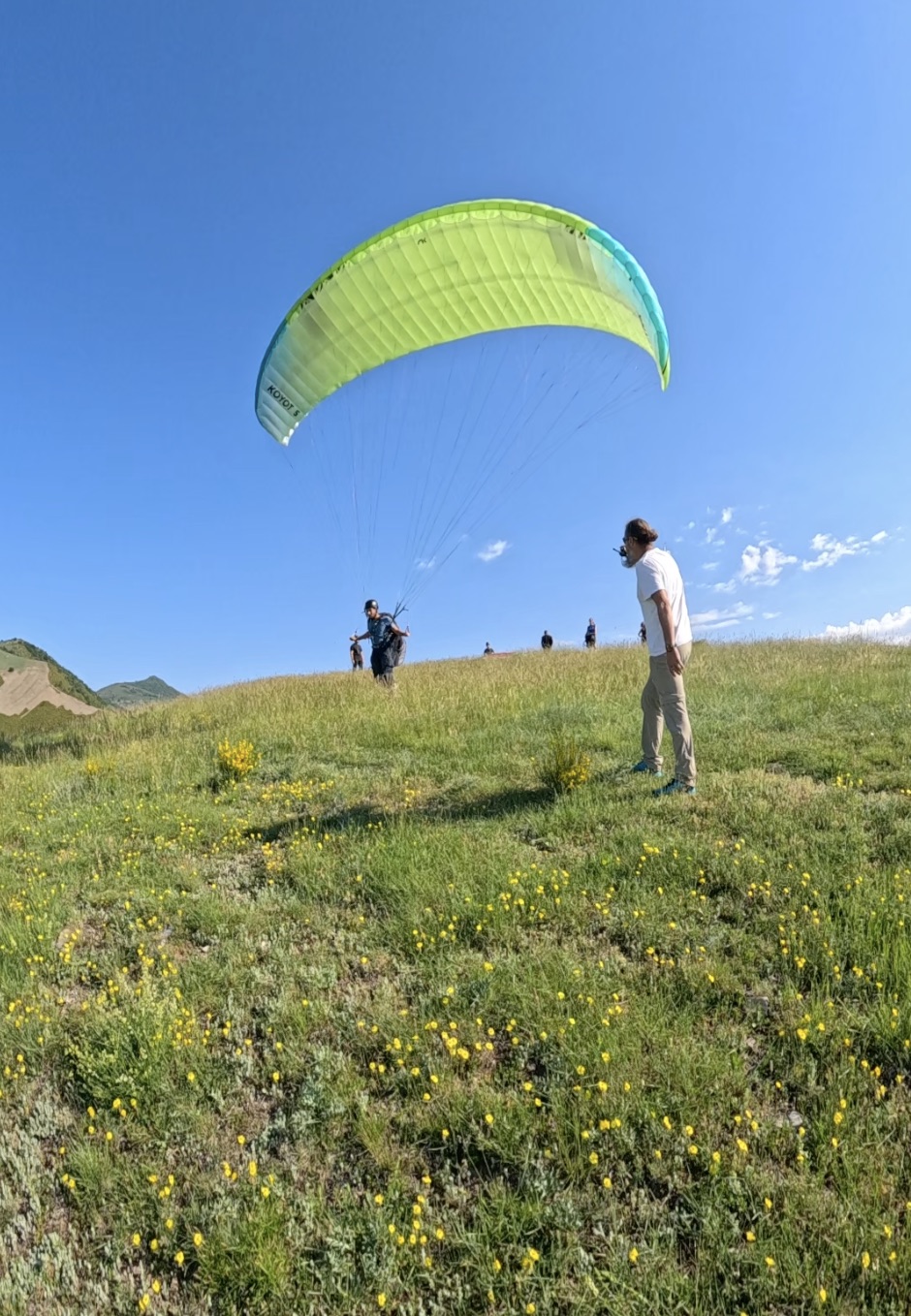 Moniteur accompagnant un pilote en parapente sur un décollage en Haute-Savoie